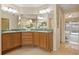 Bathroom showcasing double sinks, wood cabinets, a walk-in shower, and a view to the pool at 330 Hickory Springs Ct, Debary, FL 32713