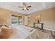 Spacious bedroom with light beige walls, tray ceilings, a ceiling fan, and sliding doors to the lanai and pool at 330 Hickory Springs Ct, Debary, FL 32713