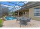 A covered patio with table and chairs overlooks the refreshing backyard pool, perfect for outdoor entertaining at 3569 Bellington Dr, Orlando, FL 32835