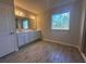 Bright bathroom featuring double vanity, wood-look tile floor, and a large window with a pleasant outdoor view at 3660 Pandora Dr, Indian Lake Estates, FL 33855