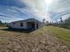 A view of the back of the house and the backyard with treeline in the distance at 3660 Pandora Dr, Indian Lake Estates, FL 33855