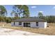 Rear view of a modern white home with sliding glass doors and large windows at 41975 Aspen St, Eustis, FL 32736