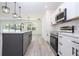 Bright kitchen overlooks living area, featuring white cabinets, stainless appliances and gray island at 41975 Aspen St, Eustis, FL 32736