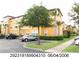 Multi-story yellow condo building with well-maintained landscaping, sidewalks, and ample parking at 5459 Vineland Rd # 4310, Orlando, FL 32811