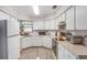 Functional kitchen featuring white cabinets, laminate countertops, modern appliances, and vinyl flooring at 59 Aberdeen Cir, Leesburg, FL 34788