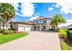 Two-story home featuring a brick driveway, tropical landscaping, and a three-car garage at 7515 John Hancock Dr, Winter Garden, FL 34787