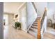 Hallway with staircase and view into living room with brick accent wall and modern furnishings at 7515 John Hancock Dr, Winter Garden, FL 34787