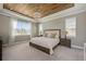 Serene main bedroom featuring a wood-paneled ceiling, soft lighting, and a large window overlooking the neighborhood at 7515 John Hancock Dr, Winter Garden, FL 34787