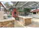 A full outdoor kitchen with a large grill, brick oven, and bar seating on the screened-in patio at 8218 Borgia Ct, Orlando, FL 32836