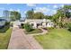 Charming single-story home with a brick driveway, lush greenery, and a glimpse of the lake at 85 Interlaken Rd, Orlando, FL 32804