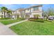 Charming two-story townhome featuring a lush green lawn, manicured bushes, and a cozy entrance with an archway at 9017 Dogleg Dr, Davenport, FL 33896