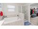 Primary bath featuring a soaking tub, glass enclosed shower, and a view into the walk-in closet at 1100 Downswing Pl, Davenport, FL 33896