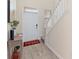 Bright entryway with wood-look flooring, a staircase, and a welcoming red-and-black checkered rug at 1100 Downswing Pl, Davenport, FL 33896