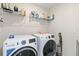 Well-equipped laundry room featuring modern washer and dryer, overhead shelving, and essential cleaning supplies at 1100 Downswing Pl, Davenport, FL 33896