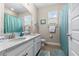 Bright bathroom featuring double sinks, granite countertop, and a blue shower curtain creating a fresh, clean space at 211 Venetian Palms Blvd, New Smyrna Beach, FL 32168