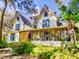 Quaint yellow two-story home with Queen Anne architecture, a screened porch, and lush, mature landscaping at 3471 Whitner Way, Sanford, FL 32773