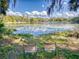Beautiful lake view with lily pads, two chairs and surrounding lush greenery under a clear blue sky at 3471 Whitner Way, Sanford, FL 32773