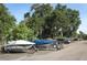 Designated boat parking area featuring various boats with covers, surrounded by trees and additional parking spaces at 626 Orange Dr # 242, Altamonte Springs, FL 32701