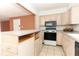 Eat-in kitchen featuring tan cabinets, black appliances, and a breakfast bar at 626 Orange Dr # 242, Altamonte Springs, FL 32701