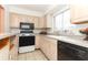 Updated kitchen with tan cabinets, black appliances, and a large sink with window view at 626 Orange Dr # 242, Altamonte Springs, FL 32701