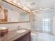 Bright bathroom with granite vanity, large mirror with decorative lighting, and glass door shower/tub at 7550 Hinson St # 11C, Orlando, FL 32819