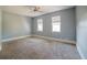 Spacious bedroom featuring neutral walls and carpet, with a ceiling fan and two windows for natural light at 8322 Lake Lucy Dr, Orlando, FL 32818