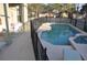 An inviting screened in pool and spa are fenced in for safety with chairs and a table to complete the area at 913 Henley Cir, Davenport, FL 33896