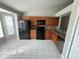 Well-lit kitchen with black appliances, brown cabinets, and a tiled floor at 1103 Jade East Ln # 1103, Kissimmee, FL 34744