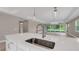 Spacious kitchen island featuring a modern faucet, stainless steel sink, and view of the sliding glass doors to the lanai at 1251 Cresswind Blvd, Deland, FL 32724