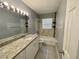 Bathroom featuring granite countertop, vanity, tub, and neutral tile at 1416 Braebury Dr, Leesburg, FL 34748