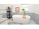 Bathroom featuring a modern soaking tub, tile accent wall, and black metal shelving at 1611 Chestnut Ave, Winter Park, FL 32789
