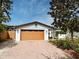 Home featuring a light-colored garage with a brick driveway and a beautiful tree in the front at 1611 Chestnut Ave, Winter Park, FL 32789