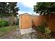 Backyard shed with wood door and black hardware is surrounded by landscaping and grass at 1611 Chestnut Ave, Winter Park, FL 32789