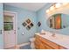 A quaint blue bathroom with a rustic vanity, decorative wall art, and an exterior door for convenient access at 22 Sweetwater Creek Cir, Oviedo, FL 32765