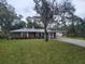 Charming single-story brick home featuring a covered carport, mature trees, and a well-maintained lawn at 2215 Hontoon Rd., Deland, FL 32720