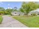 Well-maintained home featuring a long driveway, green lawn, and mature trees at 27 Foxhunter Flt, Ormond Beach, FL 32174