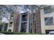 A multi-story condo building with brick and blue-painted siding, shadowed by bare trees, and green bushes at 5016 Park Central Dr # 2231, Orlando, FL 32839