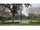 View of the community tennis court surrounded by green fencing and lush landscaping with nearby apartments at 5016 Park Central Dr # 2231, Orlando, FL 32839