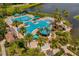 Stunning aerial view of a community pool with lush landscaping, a pirate ship slide, and lake views at 5509 Florence Harbor Dr, Orlando, FL 32829