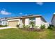 Inviting single-story home showcasing neutral stucco, solar panels, a two-car garage and manicured landscaping at 5637 Cedar Chase Dr, St Cloud, FL 34771