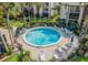 Aerial view of circular community pool with seating and tables on a paved surface with landscaping at 586 Orange Dr # 114, Altamonte Springs, FL 32701