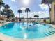Community pool with clear water and sun loungers surrounded by green landscaping with view of the lake at 586 Orange Dr # 114, Altamonte Springs, FL 32701