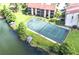 Aerial view of community tennis court next to a lake and boat dock in a lush green area at 586 Orange Dr # 114, Altamonte Springs, FL 32701