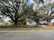 Charming blue house surrounded by large oak trees, featuring a white porch and fenced yard along the road at 9350 2Nd Ave, Orlando, FL 32824