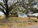 Quaint blue house with white trim, complemented by mature trees, a small front porch, and a fenced yard at 9350 2Nd Ave, Orlando, FL 32824