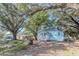 Blue house with a welcoming porch, surrounded by mature trees and a fenced yard for added privacy at 9350 2Nd Ave, Orlando, FL 32824