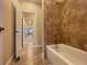 Bathroom featuring a tub shower combo with tan tile surround and an entry to a hallway at 9526 Lake Hugh Dr, Gotha, FL 34734