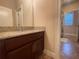 Bathroom featuring granite countertop, a view to the tub and shower, and a cabinet sink at 9526 Lake Hugh Dr, Gotha, FL 34734