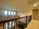 Hallway featuring dark wood railings and banisters, views of the living room, and multiple windows at 9526 Lake Hugh Dr, Gotha, FL 34734