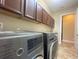 Functional laundry room with modern washer and dryer, ample cabinets, and a convenient utility sink at 9526 Lake Hugh Dr, Gotha, FL 34734